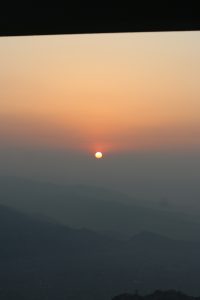 
A serene sunrise over a mountainous landscape, with a warm orange and pink sky.