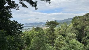 A wide view of a coastal town between green hills and a calm blue bay.