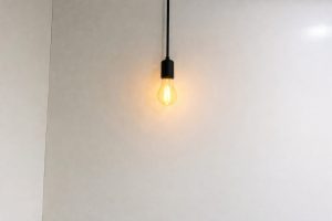 A glowing Edison-style hanging light bulb on a plain white wall.
