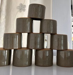A pyramid structure made of ten small, rounded ceramic cups arranged in a staggered formation. 