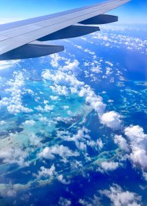 Aerial view of turquoise coral atolls and islands from an airplane window