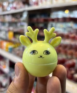 Person holding a small yellow ball with a deer design, looking playful and fun.