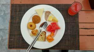 A white plate with a variety of breakfast items is displayed on a textured brown placemat.