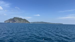 A stunning view of a calm, blue tropical lagoon enclosed by towering limestone mountains and lush vegetation.