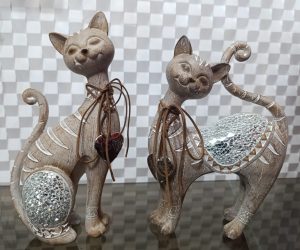 Esculturas de gatos cafés en pareja con detalles brillantes y collares decorativos.