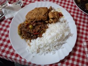 A white dish with rice, chicken, and gravy. There are two olives in the gravy. 