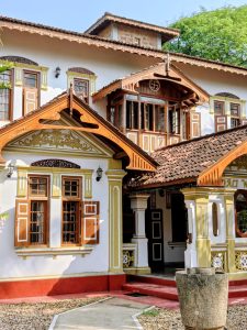Front view of Sandali Walauwa, a 155-year-old heritage mansion in Bentota, Sri Lanka, featuring wooden windows, carved gables, tiled roofs, and a central courtyard.
