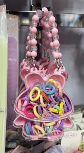 
A pink, butterfly-shaped container filled with colorful hair ties and elastics.