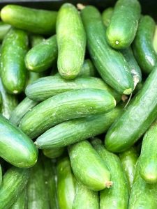 A close-up of fresh, shiny green cucumbers piled together with smooth, vibrant skin.