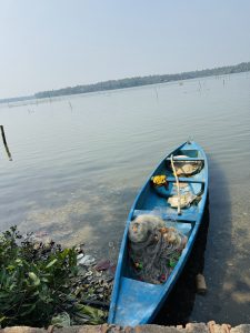 A blue boat moored on a calm Kerala river, with lush green trees in the background.