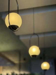 Close-up of three modern globe pendant lights with soft yellow glass. The front light is clear, while the others blur into a warm background.