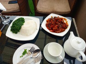A plate of posho (ugali) with goat meat in rich gravy, served with tea.