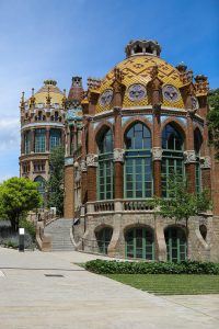 A vertical photo of an Art Nouveau building with detailed brickwork and a yellow tiled dome.