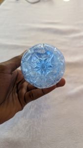 A hand holding a light blue circular object with a textured floral pattern on a white tablecloth.