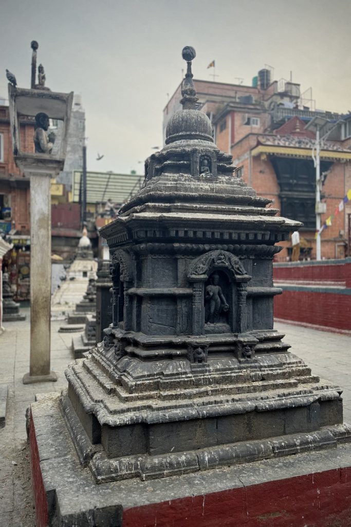 A close-up view of a stone stupa adorned with intricate carvings, situated in an outdoor area.