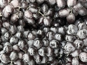 A close-up of dark purple grapes with smooth skin and round shapes.