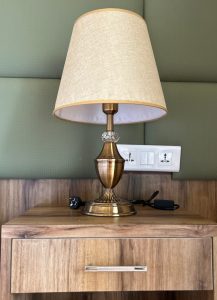 A stylish bedside lamp rests on a wooden nightstand.
