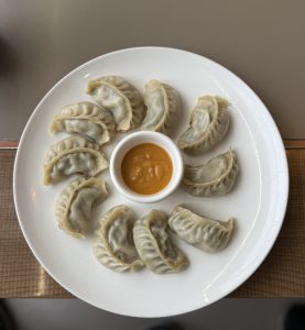 Plate of dumplings with orange dipping sauce.