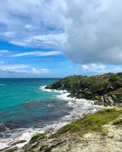 A scenic coastal view featuring rocky cliffs and vibrant turquoise waters