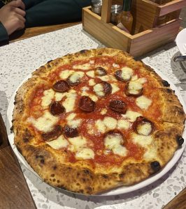 A freshly baked pizza topped with cheese and pepperoni on a white plate.