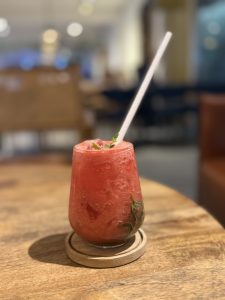 Watermelon drink with mint garnish and a straw on a wooden table.
