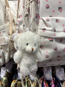 A white teddy bear resting on a pink bag, creating a soft and playful scene.  