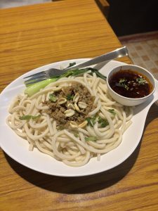 A plate of keema noodles topped with savory meat and rich sauce, garnished for an appetizing presentation.