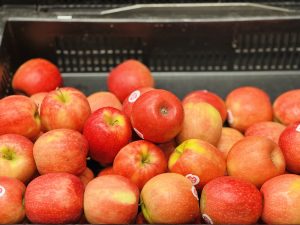 A pile of fresh red apples, some with yellow undertones, arranged in a black container. 