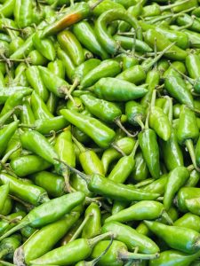 A dense cluster of vibrant green chili peppers displayed together.