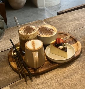 Wooden tray holds a cup of coffee and a dessert, elegantly arranged for a cozy dining experience.