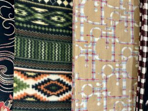 The image features a close-up view of various fabric patterns arranged vertically. The leftmost fabric has a dark background with intricate floral designs, followed by a thick, woolen fabric in shades of green with geometric and zigzag patterns. The next fabric displays an orange and cream diamond pattern set against a dark background.