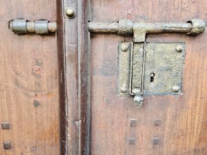 Close-up of a traditional wooden door with an old metal latch and keyhole, highlighting heritage details in Kozhikode, Kerala. 