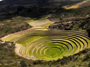 Esta imagen muestra el sitio arqueológico de Moray, ubicado en el Valle Sagrado de los Incas cerca de Cusco, Perú. Presenta un campo circular dispuesto en terrazas dentro de una depresión. This image shows the archaeological site of Moray, located in the Sacred Valley of the Incas near Cusco, Peru. It features a circular field terraced into a bowl.