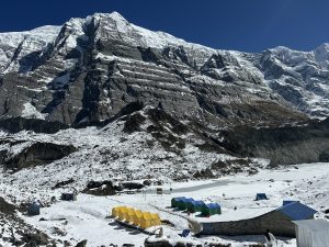 A beautiful high-altitude view of the Base Camp, with tall snow-covered mountains under a clear blue sky.
