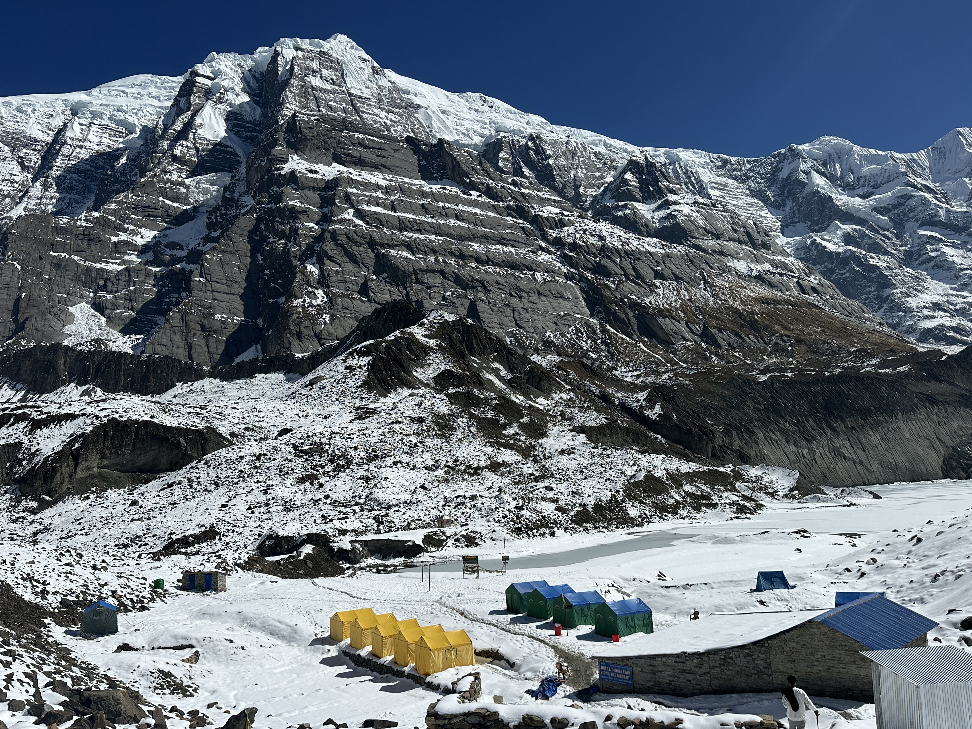 A beautiful high-altitude view of the Base Camp, with tall snow-covered mountains under a clear blue sky.
