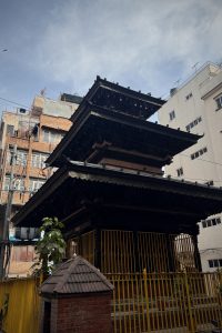 A multi-tiered pagoda-style temple made of dark wood with intricate carvings.
