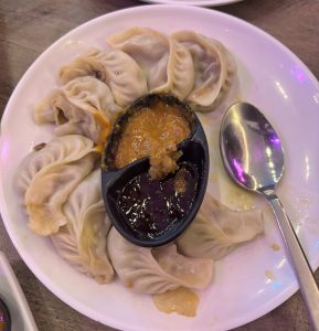 Plate of dumplings with dipping sauce and a spoon.