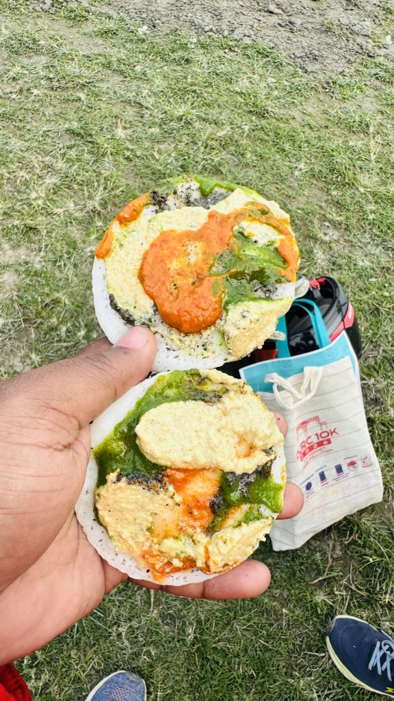 A person holds two rice cakes topped with colorful chutneys, with a grassy field in the background.