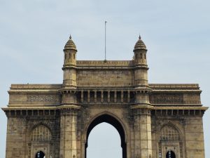 The front view of the Gateway of India in Colaba, Mumbai. The centered composition and historic structure stand out clearly against the soft sky background. 
