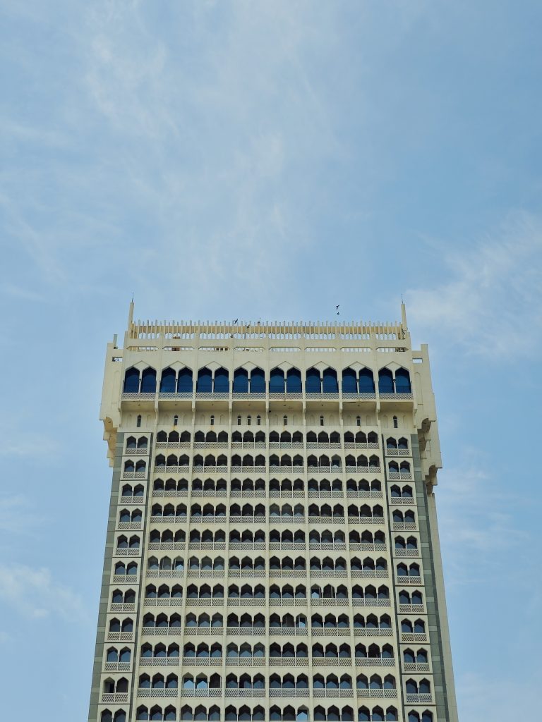 A tall modern building with repeating window patterns in Colaba, Mumbai. The simple symmetry and clean blue sky create a neat and minimal architectural view.