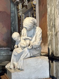 Sculpture of a woman holding a child at the entrance of the National Theatre of Costa Rica, surrounded by classical architecture and soft natural light.