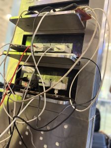 A charging station at the Mumbai Airport. Various charging cables are tangled and connected to devices and power outlets.