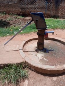 A borehole in rural Uganda with a brick wall in the background.