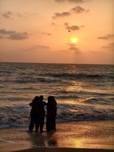 Four friends laugh and play in the waves, soaking in the golden hues of a beautiful beach sunset.