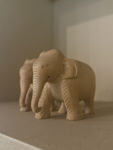 Two small wooden elephant sculptures on a shelf.