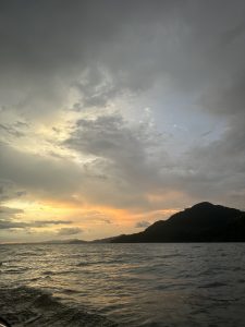 A serene seascape at sunset, showcasing gentle waves reflecting golden and orange hues on the water's surface