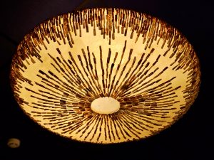 A warm, glowing ceiling lamp with detailed patterns, creating a beautiful radial design. A striking interior detail captured in Worli, Mumbai.