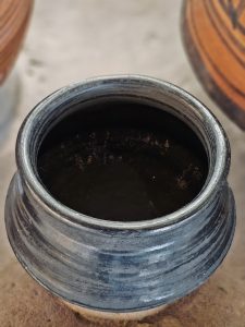 A close view of a handmade black earthen pot with natural texture and soft lighting. The background blur keeps focus on the pot. Captured in Andheri, Mumbai. 
