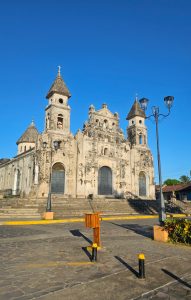 Historic colonial-style church in a quiet town square under a clear blue sky.