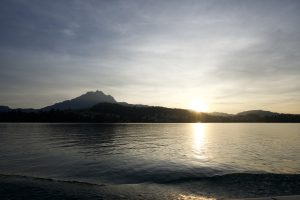 Sunset at a lake with calm water reflecting the sky and surrounding landscape.